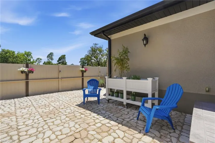 Expansive outdoor patio featuring an irregular stone paver surface, a stucco exterior wall, and a dark fascia