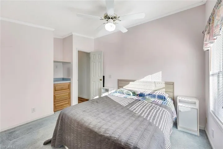Bedroom with crown molding, ceiling fan, and light carpet