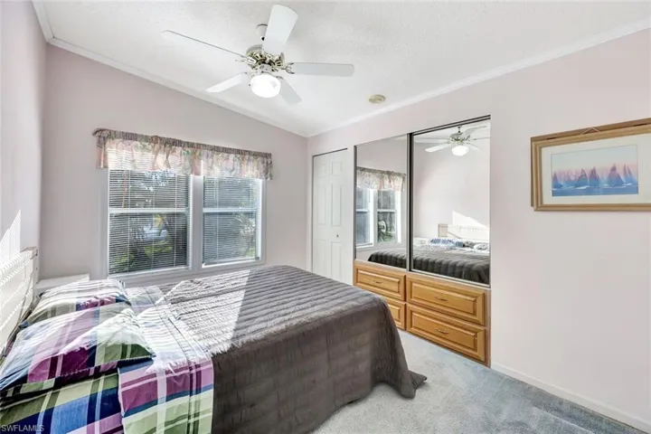 Bedroom featuring crown molding, multiple closets, carpet flooring, ceiling fan, and vaulted ceiling