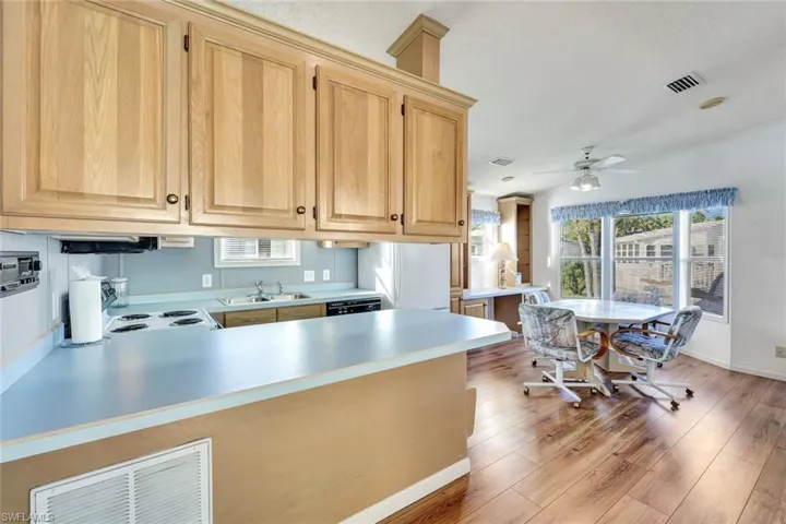 Kitchen featuring light countertops, a peninsula, light brown cabinets, ceiling fan, and range with electric cooktop