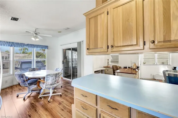 Kitchen with light brown cabinetry, light countertops, light wood-type flooring, a ceiling fan, and a textured ceiling