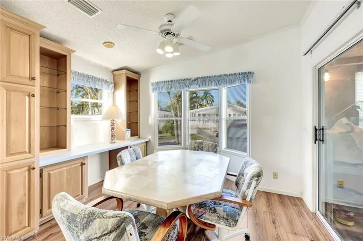 Dining room featuring lofted ceiling, light wood-type flooring, a textured ceiling, ceiling fan, and ornamental molding