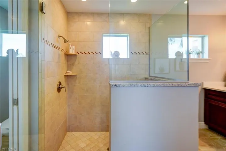 Bathroom featuring toilet, vanity, and tiled shower