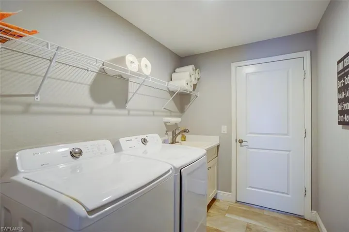 Clothes washing area with washing machine and dryer, cabinets, and sink
