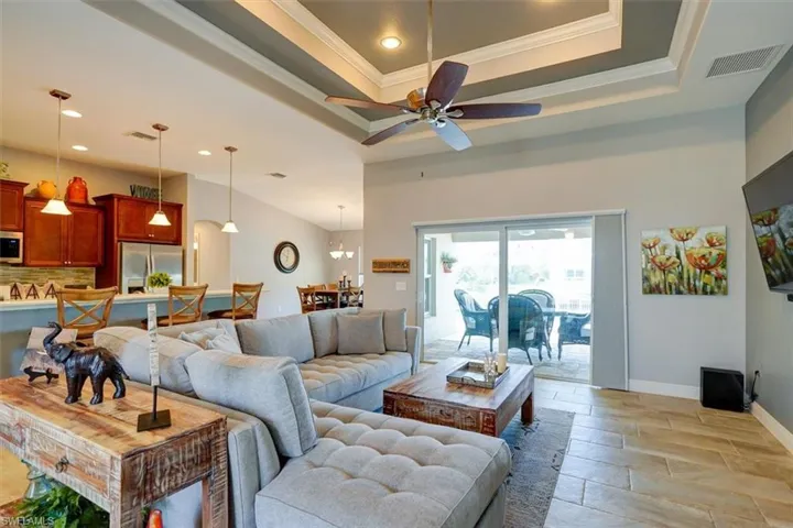Living room featuring ceiling fan, a raised ceiling, light hardwood / wood-style flooring, and ornamental molding