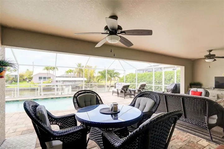 View of patio featuring glass enclosure, outdoor lounge area, a grill, and ceiling fan