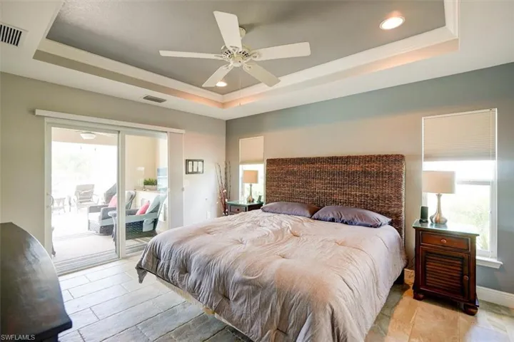 Bedroom featuring a tray ceiling, ceiling fan, and access to exterior