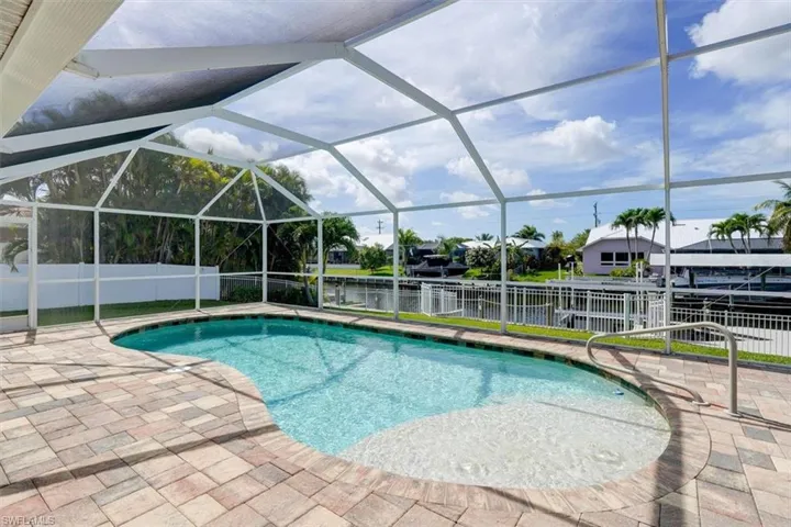 View of pool with a patio, a water view, and glass enclosure