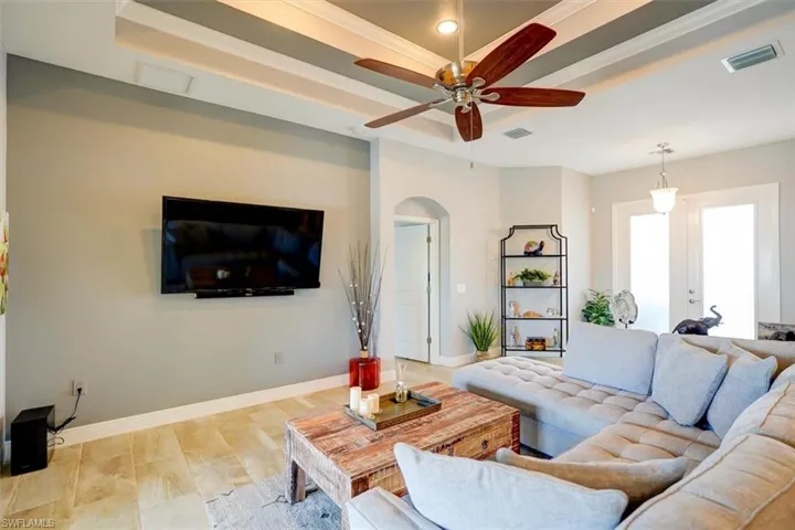 Living room with french doors, light hardwood / wood-style floors, ornamental molding, ceiling fan, and a tray ceiling