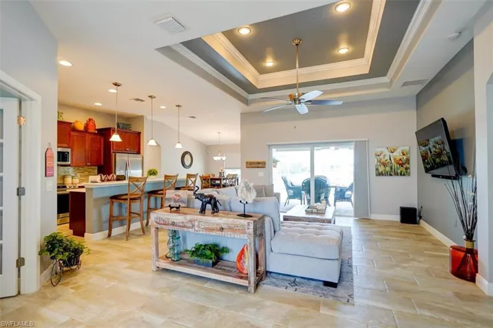 Living room with ceiling fan, a raised ceiling, and crown molding