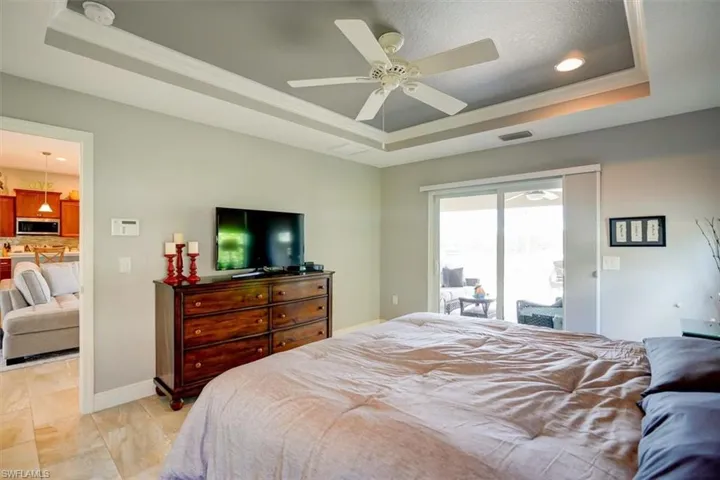 Bedroom with access to outside, ceiling fan, crown molding, and a tray ceiling