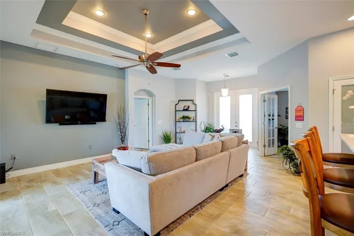 Living room with crown molding, french doors, ceiling fan, and a raised ceiling