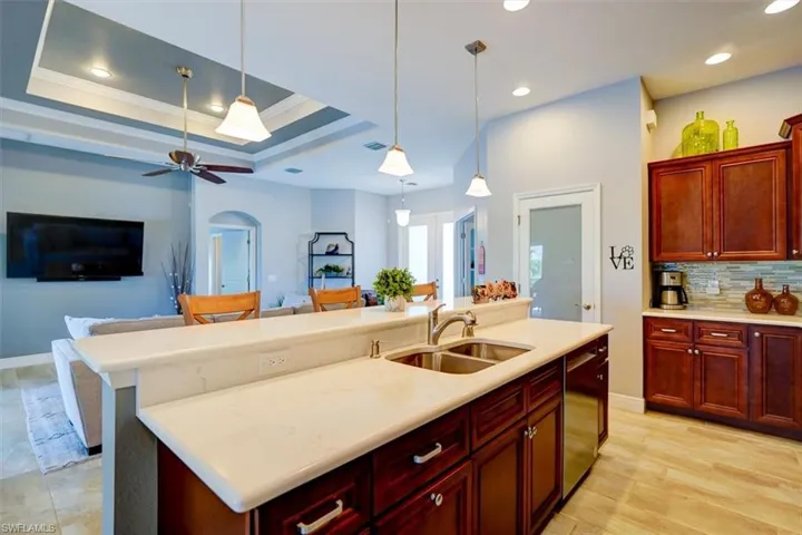 Kitchen featuring backsplash, stainless steel dishwasher, sink, and pendant lighting