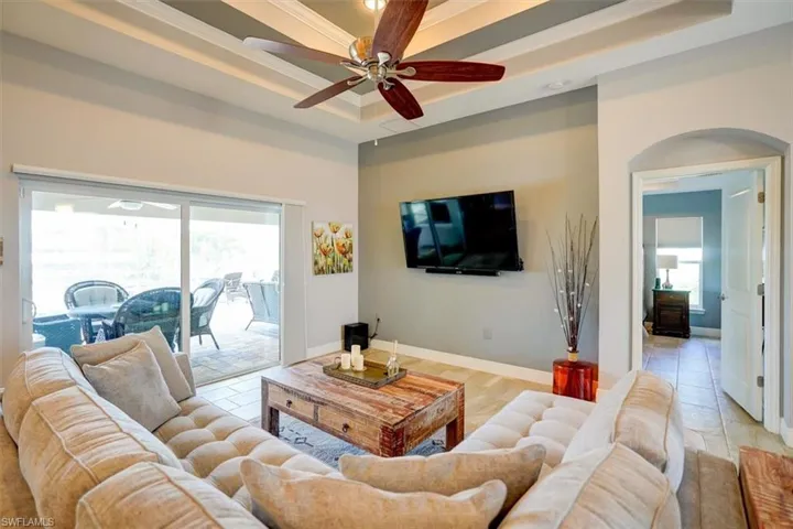 Living room featuring light hardwood / wood-style flooring, a tray ceiling, ceiling fan, and crown molding