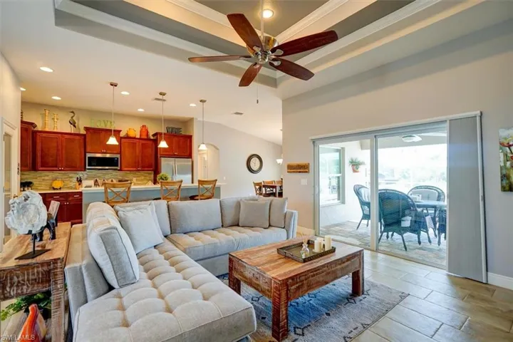 Living room with ornamental molding, ceiling fan, and a tray ceiling