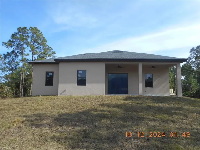 Rear view of property featuring a yard and ceiling fan