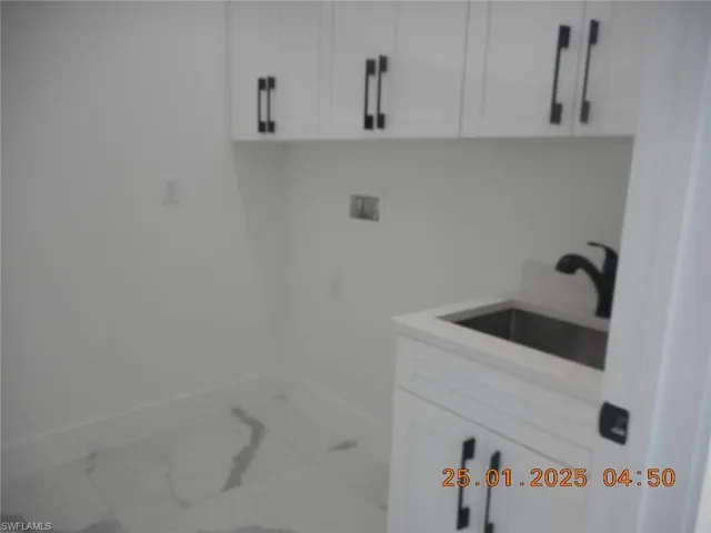 Washroom featuring cabinets, hookup for a washing machine, and sink