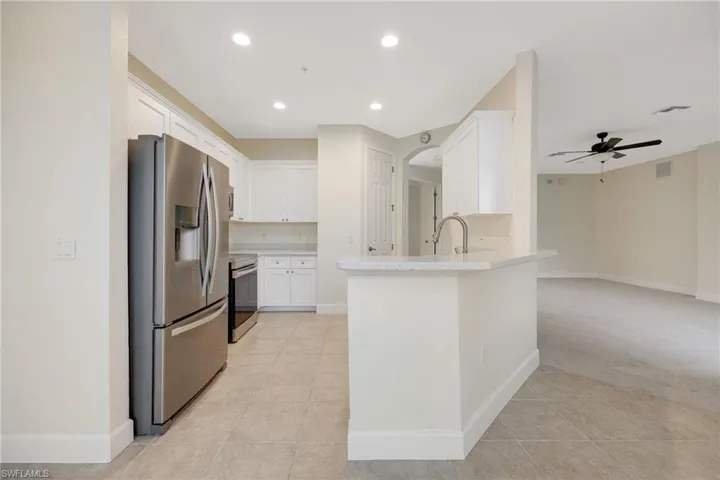 Kitchen featuring light carpet, ceiling fan, appliances with stainless steel finishes, sink, and white cabinetry