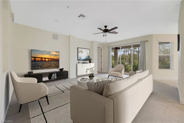 Living area featuring light colored carpet and a ceiling fan
