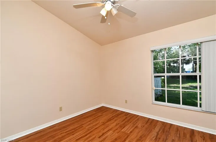 Unfurnished room featuring wood finished floors, a ceiling fan, and vaulted ceiling