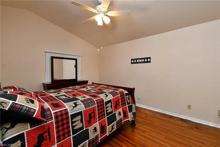 Bedroom with lofted ceiling, wood finished floors, and ceiling fan