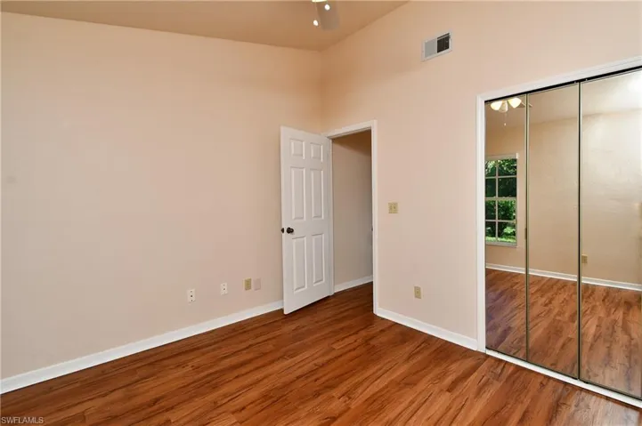 Unfurnished bedroom featuring wood finished floors, a closet, and a high ceiling
