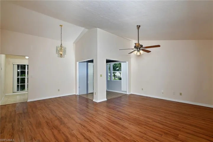 living room with lofted ceiling, ceiling fan, wood finished floors, and a chandelier