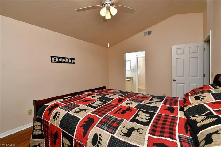 Bedroom with vaulted ceiling, wood finished floors, a ceiling fan, and ensuite bathroom
