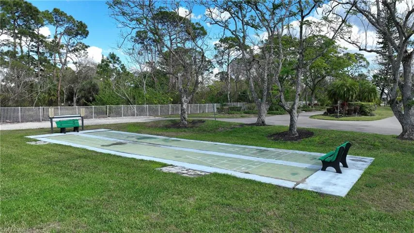 Surrounding community featuring shuffleboard and view of wooded area
