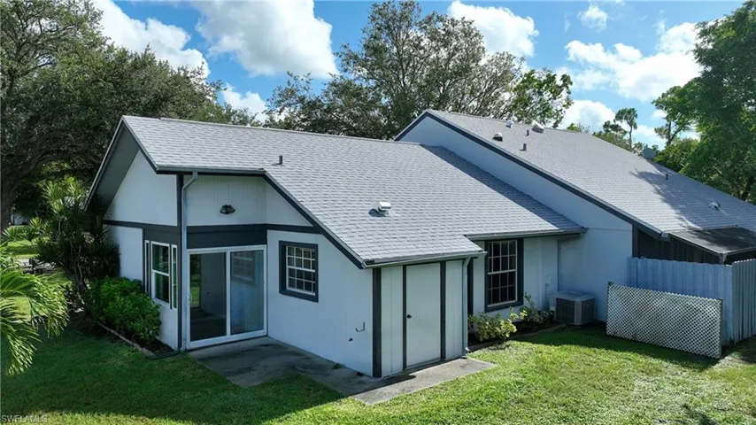 Rear view of property with a lawn and a shingled roof