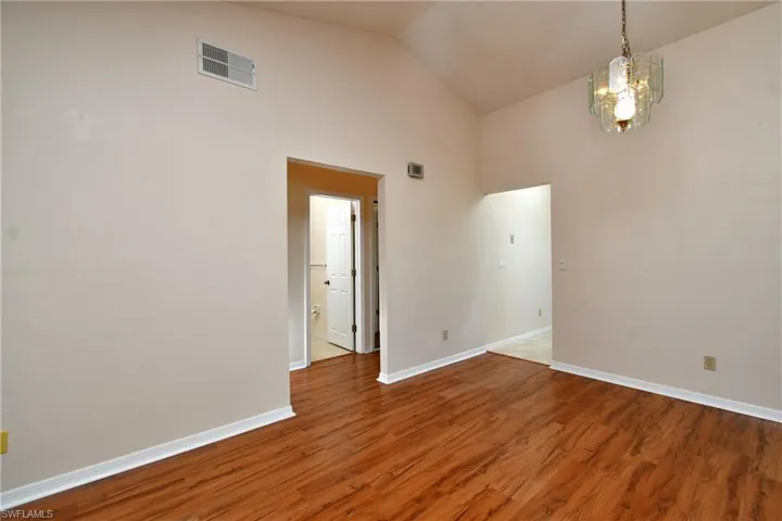 Empty room featuring high vaulted ceiling and wood finished floors