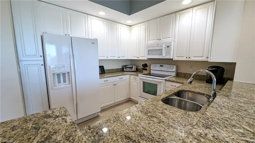 Kitchen featuring white cabinetry, granite counters, and white appliances