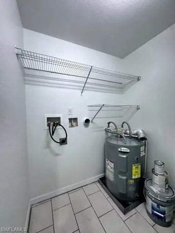 Laundry room featuring electric water heater, hookup for a washing machine, and light tile patterned flooring