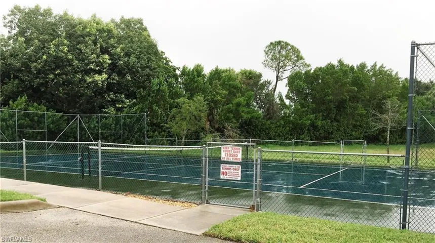 View of tennis court with a gate