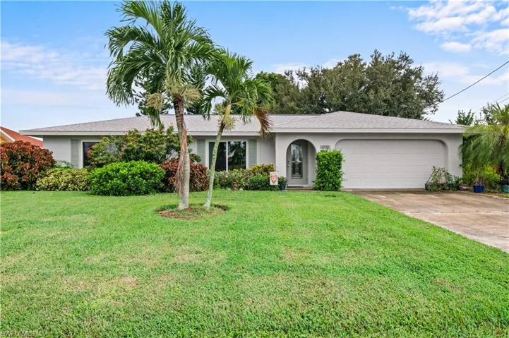 Ranch-style home featuring a front yard, driveway, stucco siding, and an attached garage