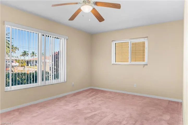 Guest bedroom #1 with light carpet and a ceiling fan