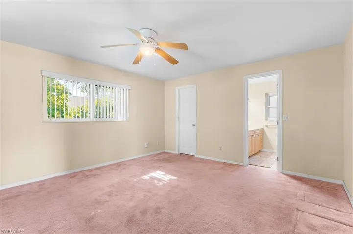 Primary bedroom with ceiling fan, and connected bathroom