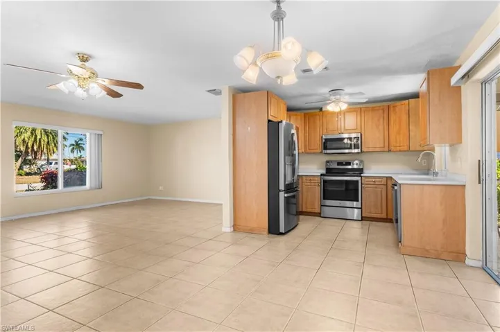 Kitchen with open floor plan, light countertops, a ceiling fan, and appliances with stainless steel finishes