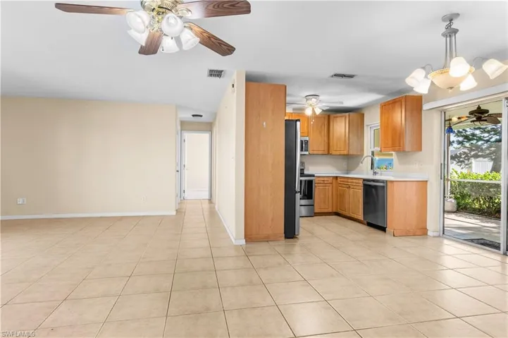 Kitchen featuring a ceiling fan, light countertops, a chandelier, hanging light fixtures, and appliances with stainless steel finishes
