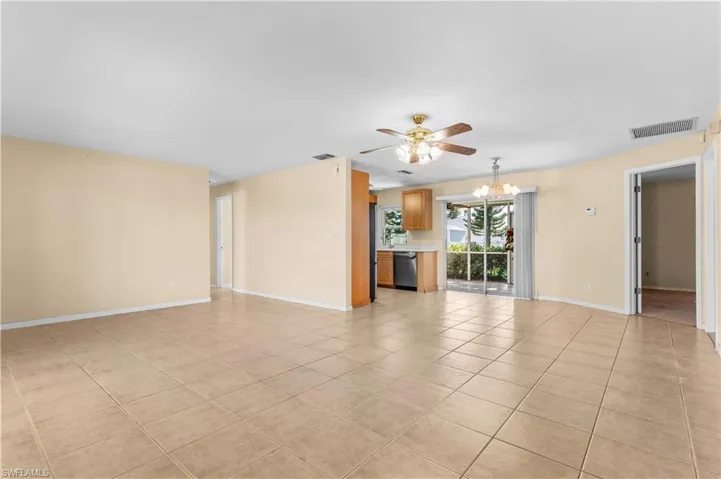 Unfurnished living room with a chandelier, light tile patterned floors, and a ceiling fan
