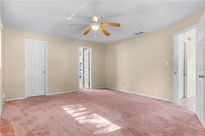 Primary bedroom featuring light carpet and a ceiling fan