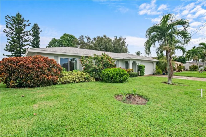 Ranch-style home with a garage, driveway, and a front lawn