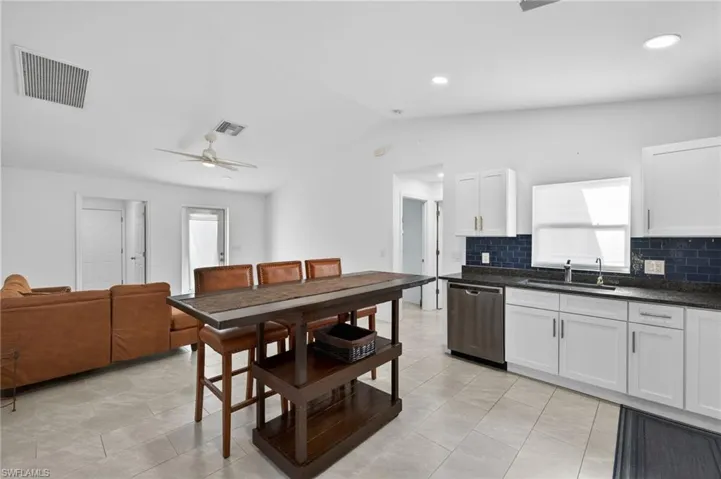 Kitchen featuring a ceiling fan, dishwasher, white cabinetry, tasteful backsplash, and dark stone counters