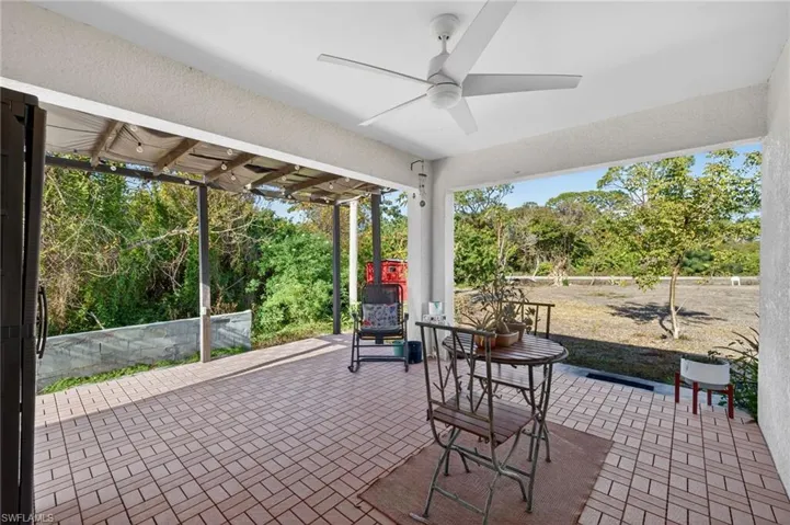 View of patio with a ceiling fan and view of scattered trees