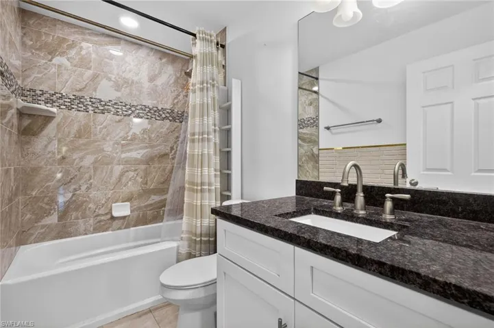 Bathroom featuring shower / bath combination with curtain, vanity, and light tile patterned floors