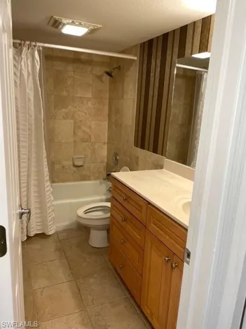 Full bathroom with vanity, shower / bath combo, a textured ceiling, and light tile patterned floors
