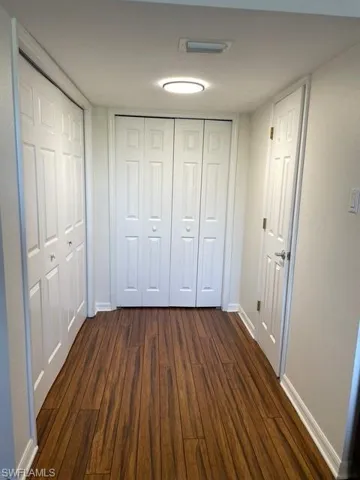 Unfurnished bedroom with dark wood-style floors and two closets