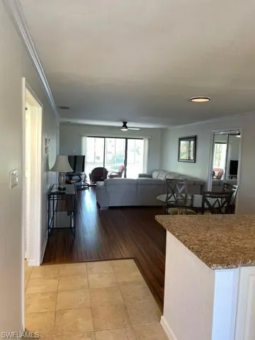 Living room with light tile patterned floors, ornamental molding, and a ceiling fan