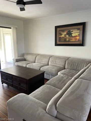 Living room featuring wood finished floors, crown molding, and ceiling fan