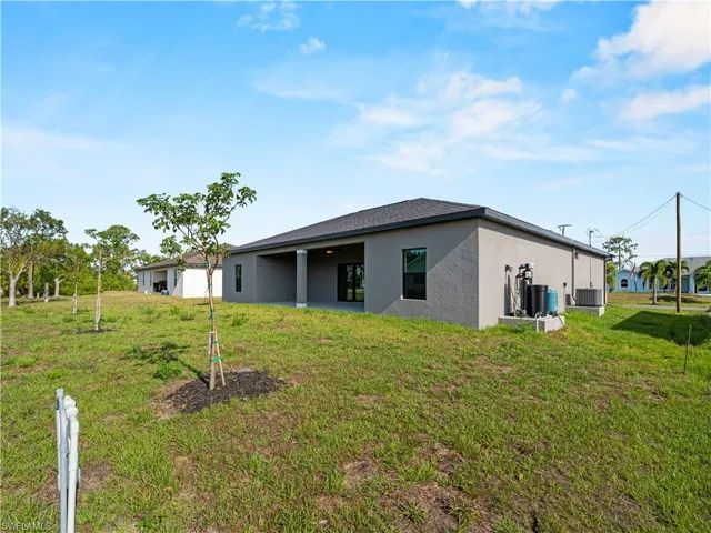 Back of house with stucco siding, a yard, and cooling unit